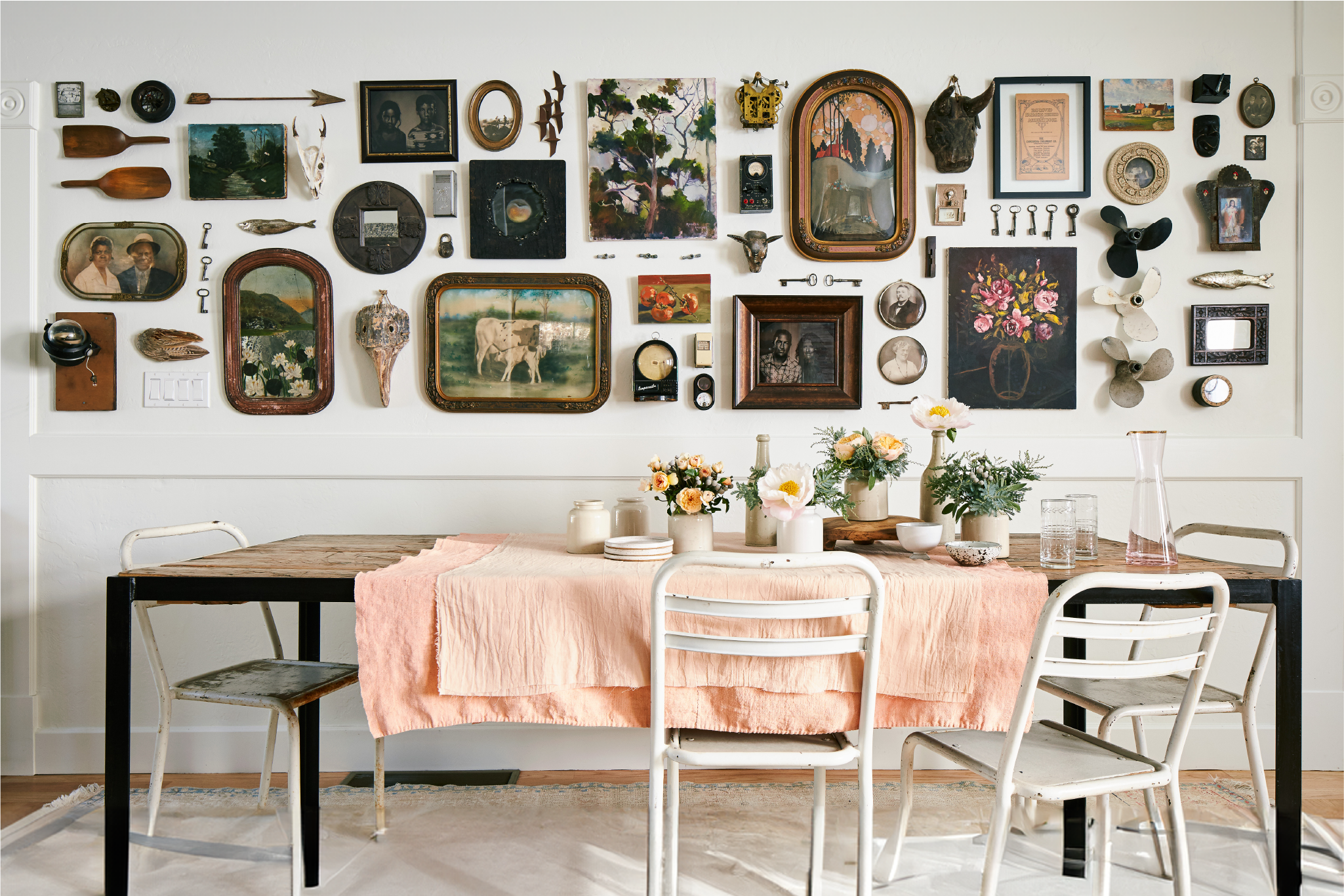 A wall decorated with pictures, paintings, mirrors, textiles, plants